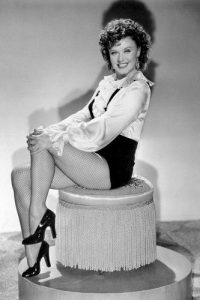 Ginger Rogers as Roxie Hart sitting on a chair in a publicity photo